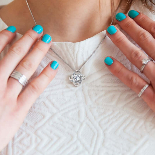 Woman admiring a silver pendant necklace with turquoise nail polish, highlighting its elegance and suitability as a romantic gift.