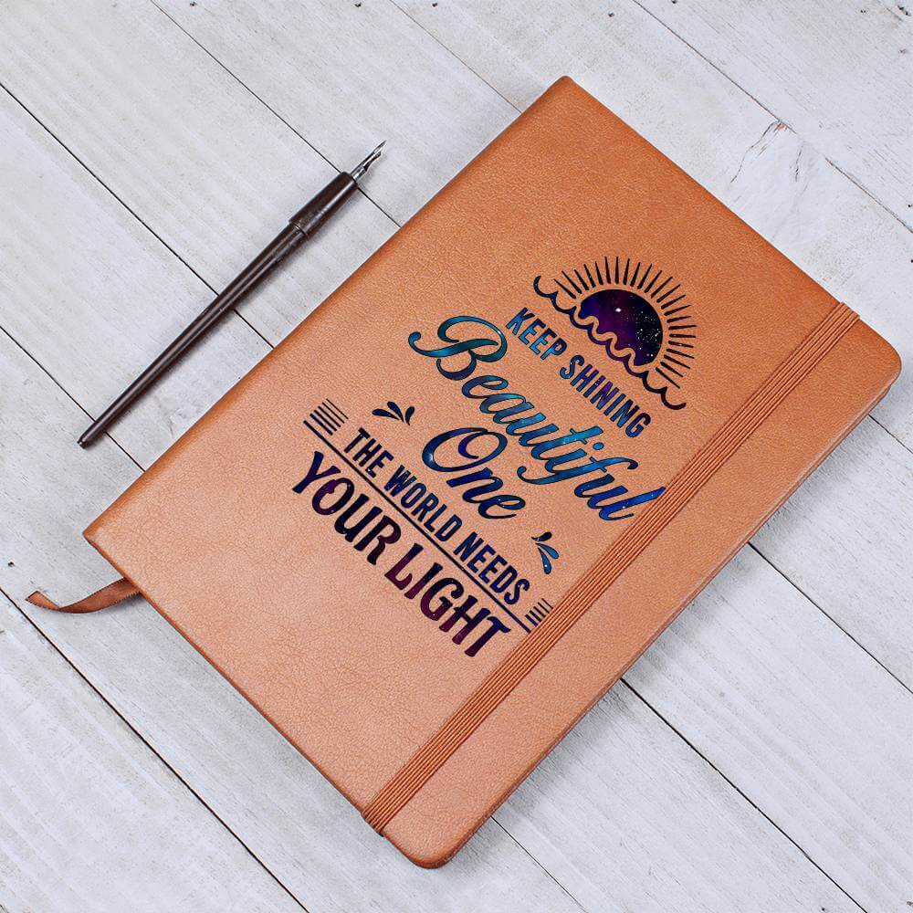 Keep Shining Beautiful One - Graphic Leather JournalVenture beyond with the Graphic Leather Journal. Ideal for goal setting and organization, it features a bookmark and elastic closure.Moving Phrases