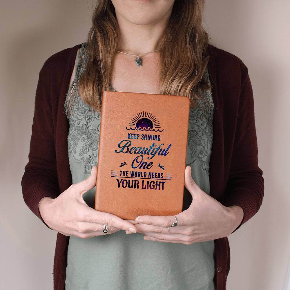 Keep Shining Beautiful One - Graphic Leather JournalVenture beyond with the Graphic Leather Journal. Ideal for goal setting and organization, it features a bookmark and elastic closure.Moving Phrases