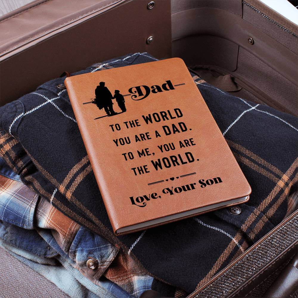 Dad, to the World you are - Graphic Leather JournalVenture beyond with the Graphic Leather Journal. Ideal for goal setting and organization, it features a bookmark and elastic closure.Moving Phrases