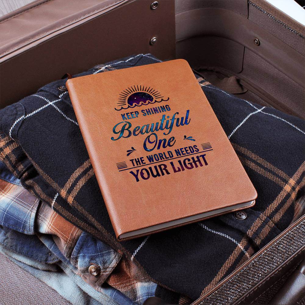 Keep Shining Beautiful One - Graphic Leather JournalVenture beyond with the Graphic Leather Journal. Ideal for goal setting and organization, it features a bookmark and elastic closure.Moving Phrases