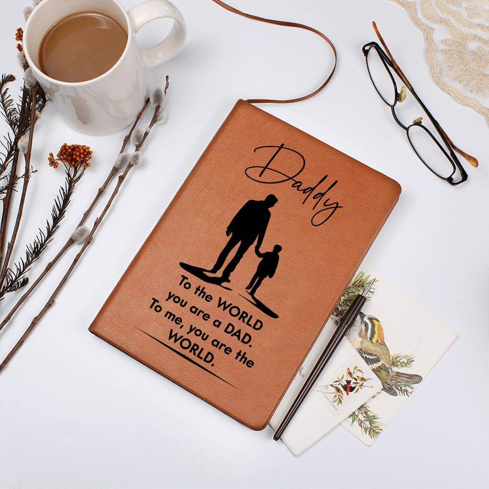 Daddy, to the World you are a Dad - Graphic Leather JournalVenture beyond with the Graphic Leather Journal. Ideal for goal setting and organization, it features a bookmark and elastic closure.Moving Phrases