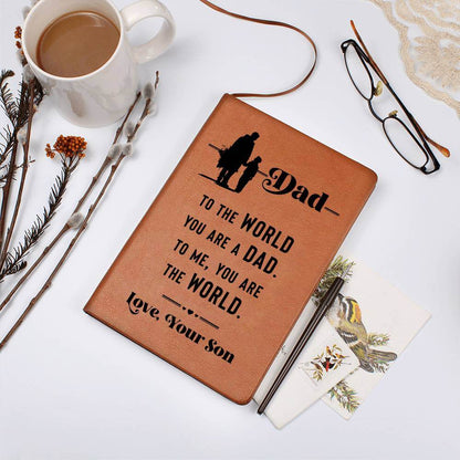 Dad, to the World you are - Graphic Leather JournalVenture beyond with the Graphic Leather Journal. Ideal for goal setting and organization, it features a bookmark and elastic closure.Moving Phrases