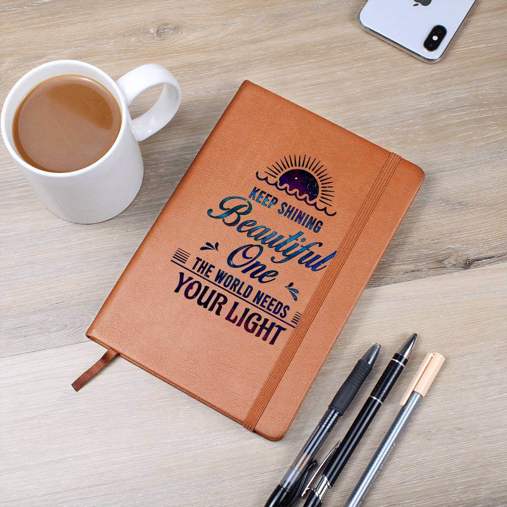 Keep Shining Beautiful One - Graphic Leather JournalVenture beyond with the Graphic Leather Journal. Ideal for goal setting and organization, it features a bookmark and elastic closure.Moving Phrases