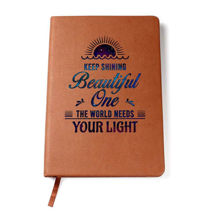 Keep Shining Beautiful One - Graphic Leather JournalVenture beyond with the Graphic Leather Journal. Ideal for goal setting and organization, it features a bookmark and elastic closure.Moving Phrases