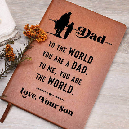 Dad, to the World you are - Graphic Leather JournalVenture beyond with the Graphic Leather Journal. Ideal for goal setting and organization, it features a bookmark and elastic closure.Moving Phrases