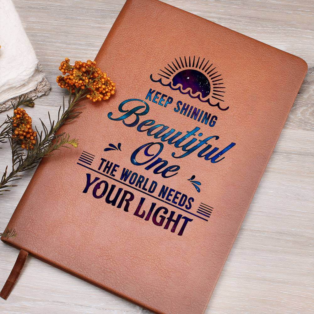 Keep Shining Beautiful One - Graphic Leather JournalVenture beyond with the Graphic Leather Journal. Ideal for goal setting and organization, it features a bookmark and elastic closure.Moving Phrases