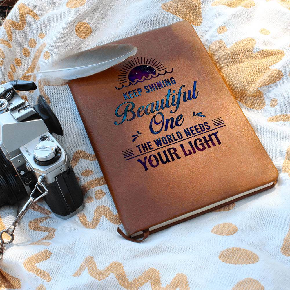 Keep Shining Beautiful One - Graphic Leather JournalVenture beyond with the Graphic Leather Journal. Ideal for goal setting and organization, it features a bookmark and elastic closure.Moving Phrases